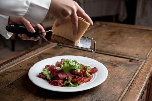 a person holding a piece of bread and a plate of food at Penserhof - Alpine Hotel & Restaurant in Sarntal