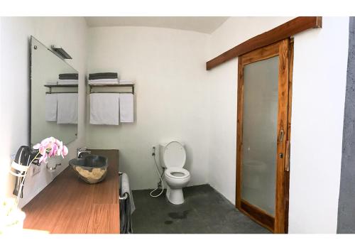a bathroom with a toilet and a wooden door at Villa Manayasa in Lovina