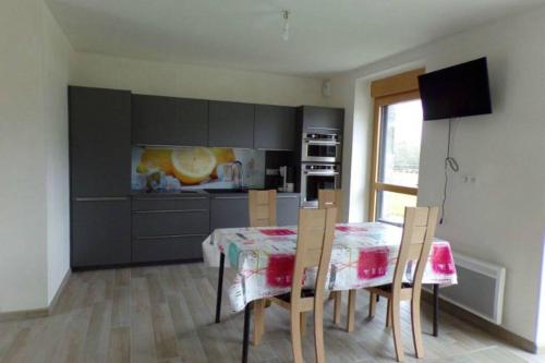 une cuisine avec une table et des chaises dans une pièce dans l'établissement LE HERON - LES VERGERS DE GUERLEDAN, à Guerlédan