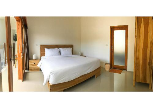 a bedroom with a large white bed and a mirror at Villa Manayasa in Lovina