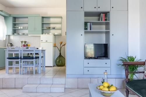 a kitchen with white cabinets and a table with a bowl of fruit at Lithos Apartments in Skopelos Town