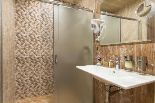 een badkamer met een douche, een wastafel en een spiegel bij Boutique Apartments - Sevtopolis in Kazanlik