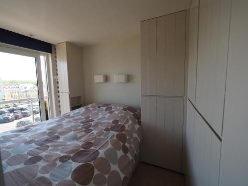 een slaapkamer met een bed en een groot raam bij Appartement sur la digue - De Haan - Le Coq - Silver Beach D2 in De Haan