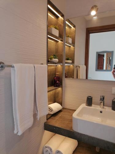 a bathroom with a sink and a mirror and towels at Hotel Antica Cascina Del Golfo in Scopello