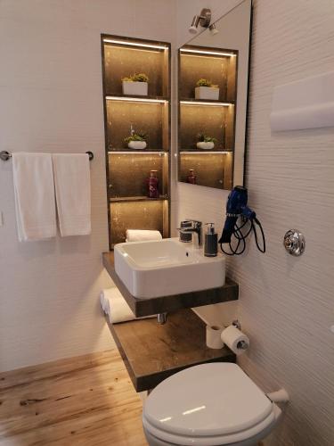 a bathroom with a sink and a toilet and a mirror at Hotel Antica Cascina Del Golfo in Scopello