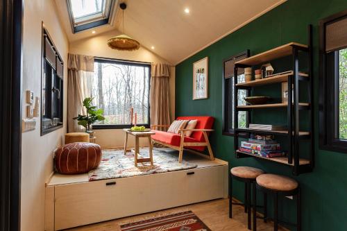 una sala de estar con paredes verdes y una silla roja. en TinyParks Forest Cabins, en Hoogersmilde