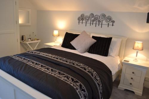 a bedroom with a large bed with two tables and two lamps at Coed-y-Fron in Betws-y-coed