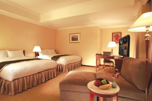 a hotel room with two beds and a couch at Grand Boss Hotel in Yilan City