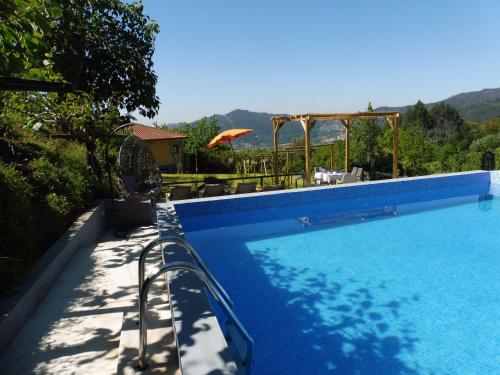 una gran piscina azul con sombrilla en Quinta da Tapada, en Longos
