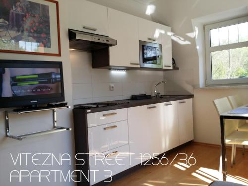 a kitchen with white cabinets and a tv on the wall at Holiday Apartments Vítězná 1256/36 in Karlovy Vary