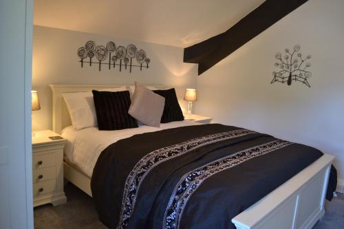 a bedroom with a large bed with black and white pillows at Coed-y-Fron in Betws-y-coed