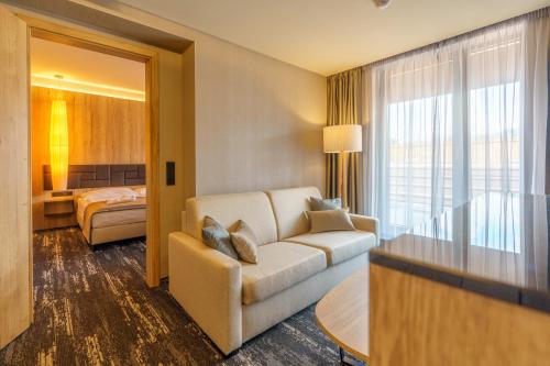 a living room with a couch and a bedroom at Hotel Hills in Tatranská Lomnica