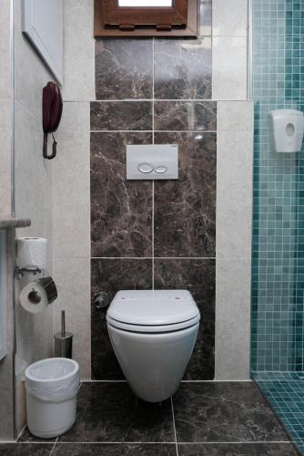 a bathroom with a toilet and a tiled wall at Club Turtas Beach - All Inclusive in Konaklı