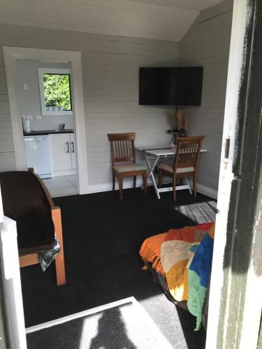 a living room with a table and chairs and a television at Stump Cottage in Lumsden