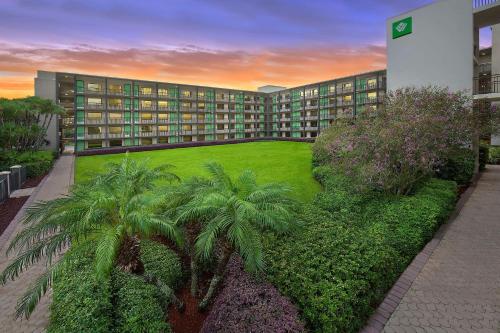 a large building with palm trees in front of it at Wyndham Garden Lake Buena Vista Disney Springs® Resort Area in Orlando