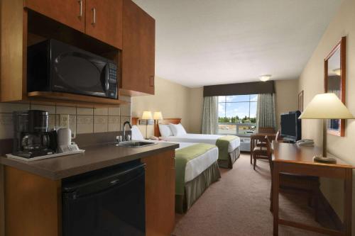 um quarto de hotel com um quarto com uma cama e uma cozinha em Super 8 by Wyndham Fort St. John BC em Fort Saint John