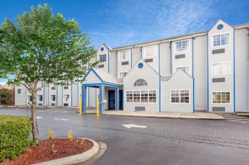 a large white building with a tree in front of it at Microtel Inn & Suites by Wyndham Matthews/Charlotte in Matthews