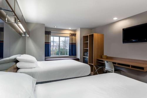 a hotel room with two beds and a flat screen tv at Microtel Inn & Suites by Wyndham Matthews/Charlotte in Matthews