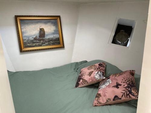 um sofá com duas almofadas e uma foto na parede em Romantic Houseboat em Amsterdã