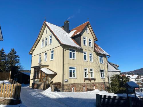 una casa grande con nieve en el suelo en BERGLAGE - Das UrlaubZuhause, en Braunlage