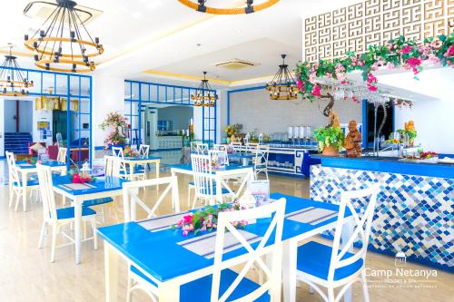 Camp Netanya Resort and Spa في مابيني: مطعم بالطاولات الزرقاء والكراسي البيضاء