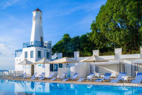 a pool with chairs and a lighthouse in the background at Camp Netanya Resort and Spa in Mabini