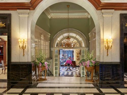 a lobby with an archway and flowers in vases at The Savoy in London