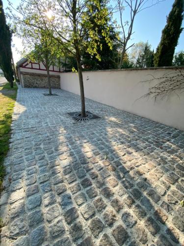 two trees on a brick sidewalk next to a wall at LA RÉSERVE DE L'AUBE - Hébergements insolites Luxe et Design in Villenauxe-la-Grande