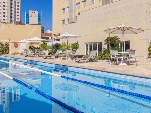 a swimming pool with chairs and tables and umbrellas at Mercure Sao Paulo Vila Olimpia in São Paulo