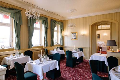 a dining room with tables and chairs and chandeliers at Ringhotel Schloss Tangermünde in Tangermünde