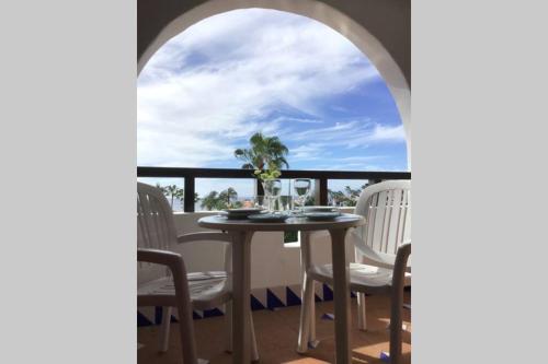 a table and chairs on a balcony with a view of the ocean at Apartamento frente al mar! in Playa de las Americas