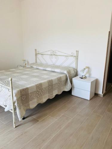 a bedroom with a white bed and a wooden floor at Agriturismo Azzarone in Vieste