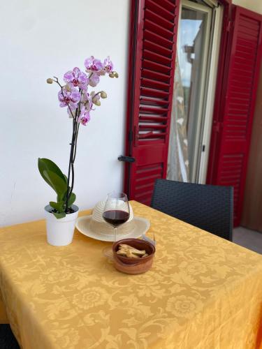 a yellow table with a glass of wine and a flower at Agriturismo Azzarone in Vieste