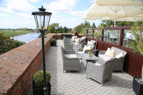 a patio with chairs and tables and an umbrella at Ringhotel Schloss Tangermünde in Tangermünde