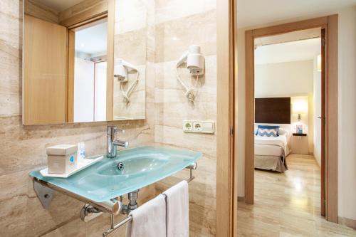 a bathroom with a blue sink and a bedroom at Grupotel Dunamar in Can Picafort
