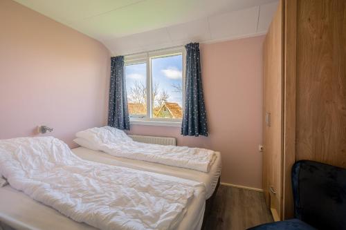 2 camas en una habitación pequeña con ventana en Nieuwlanderweg 63, en De Waal