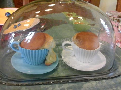 two muffins and cups on plates in a glass dome at B&B Nuraximannu in Santadi