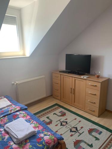 a bedroom with a bed and a tv on a dresser at Haus Kristina in Csopak
