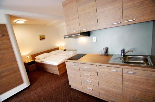 uma cozinha com uma cama e um lavatório num quarto em Hotel Lučivná em Lučivná