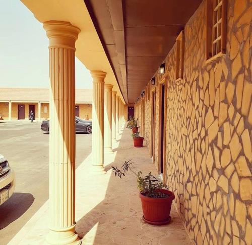 a row of columns on a building with potted plants at Desert Rose Motel in Al Ghāţ