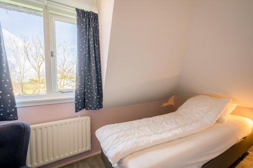 Habitación pequeña con cama y ventana en Nieuwlanderweg 61, en De Waal