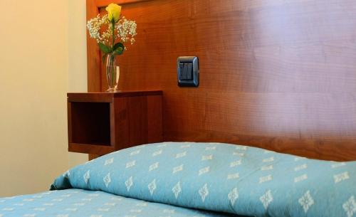 a bed with a vase with flowers in a room at Hotel Fondovalle in Città della Pieve