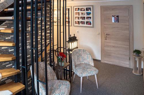 two chairs and a table in a room with a staircase at Pension Hotel Sartor in Kurort Altenberg