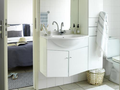 a white bathroom with a sink and a bed at 12 persoons accommodatie in Loosdrecht