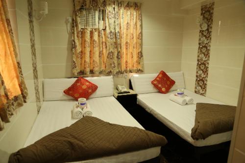 2 camas en una habitación con cortinas y ventanas en Narli Guest House, en Hong Kong