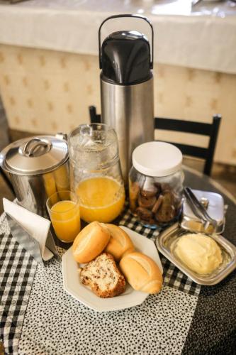 a table with a plate of bread and orange juice at Pousada Rio Branco Nova Lima in Nova Lima