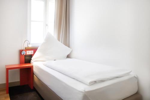 a bed in a room with a window at KU Hotel by WMM Hotels in Kulmbach