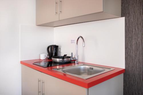 a kitchen with a sink and a red counter top at KU Hotel by WMM Hotels in Kulmbach