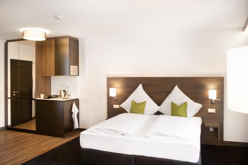 a bedroom with a large white bed and a kitchen at KU Hotel by WMM Hotels in Kulmbach