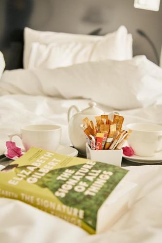 a bed with a book and some cups and cups at DysArt Boutique Hotel - Solar Power in Cape Town